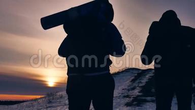 人们冬天剪影雪光.. 一群游客走在夕阳的剪影山上。 慢视频